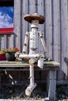 a wooden man with a hat sitting on a bench photo