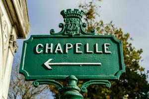 a green street sign that says chapelle with an arrow photo