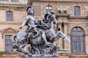 a statue of a man on a horse in front of a building photo