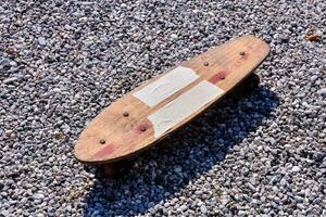 a wooden skateboard on gravel photo