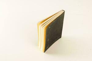 un negro cuaderno con amarillo paginas en un blanco superficie foto