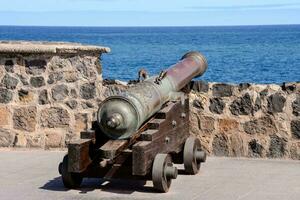 an old cannon on a stone wall near the ocean photo