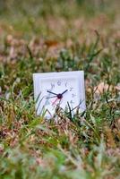 a small clock sitting in the grass photo