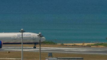 PHUKET, THAILAND FEBRUARY 20, 2023 Boeing 777, RA 73135 of Aeroflot taxiing on the runway at Phuket airport. Side view of airplane at taxiway. Blue sea background. Airport on island video