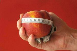 a person holding an apple with a measuring tape around it photo