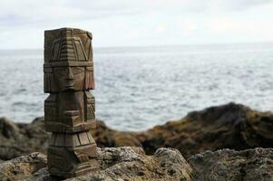 a wooden totem on the rocks by the ocean photo