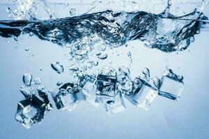 ice cubes falling down. ice cubes on blue background. splash on blue. ice cubes in water photo