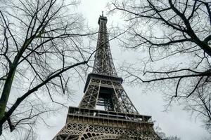 el eiffel torre es visto desde abajo con desnudo arboles foto