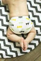 Baby boy in Eco cloth diaper on children's rug. Zero waste, eco-friendly concept. Top view photo