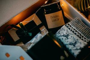 Close-up of Christmas gift box. Cozy mug for coffee, warm gray socks, aroma candle in jar. photo