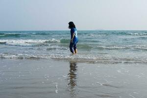 Happiness of Asian woman joyful with sea and wave on the sand beach in sunset. Freedom lonely life on vacation photo