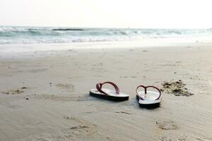 Sandals and shoes footprints on the beach and blue sea. photo