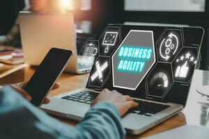 Business agility concept, Business person using laptop compuer on desk with business agility icon on virtual screen. photo