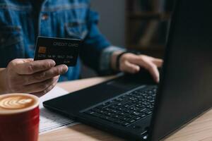 businessman uses a computer laptop and credit card to buy or purchase produce payment online and sits on the chair in the living room at home. The concept of finance and online shopping. photo