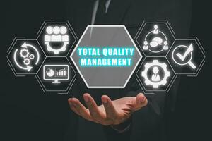 Total quality management concept, Businessman hand holding total quality management icon on virtual screen. photo
