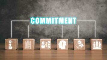 Commitment concept, Wooden block on desk with commitment icon on virtual screen. photo