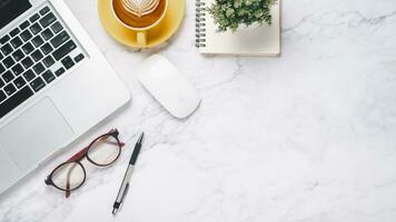 Flat lay, White office desk with laptop computer, eyeglass, pen, mouse, notebook and coffee, Top view with copy space. photo