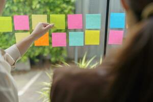 Business People working on sticky notes creative writing down ideas on post it notes professional investor start up project business. photo