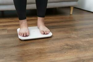 Fat diet and scale feet standing on electronic scales for weight control. Measurement instrument in kilogram for a diet control. photo