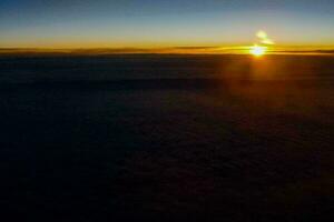 the sun is setting over the clouds as seen from an airplane photo