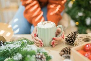 Woman holding cup of aromatic cocoa with marshmallows. Christmas eve with cup of tasty hot chocolate cozy holiday atmosphere at home photo