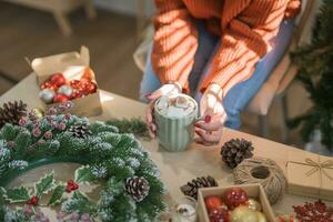 Woman holding cup of aromatic cocoa with marshmallows. Christmas eve with cup of tasty hot chocolate cozy holiday atmosphere at home photo