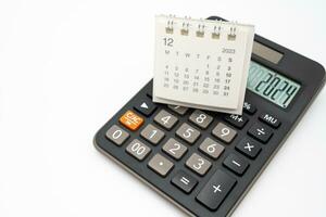 Calculator with the number 2024 on the display and Calendar DEC 2023. Concept of finance, taxes, savings and economic crisis. schedule, timetable and management of job. Business and tax concept. photo