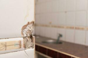 Close up of a cracked ceramic tiles surface. Cracked, broken bathroom wall tiles or panels. photo