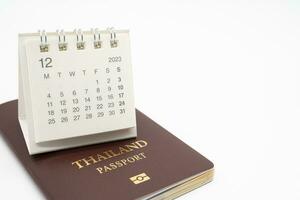 sencillo escritorio calendario para diciembre 2023 y pasaporte. calendario y fiesta concepto con pasaporte aislar en blanco antecedentes. foto
