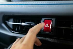 presses the emergency stop button in the car. Car emergency warning light button in front car console. photo