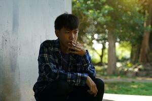 A teenage boy secretly comes to sit and smoke alone in a hidden corner of the school. which is the substance use behavior of teenagers who have life problems. soft and selective focus. photo