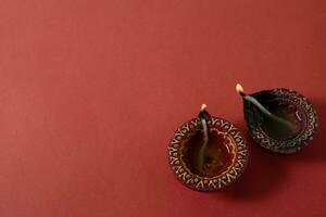 Happy Diwali and Kartika Deepam Festival Greetings - Colorful clay diya lamps on red background photo