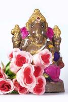 A Ganesh statue made of clay is also a rose flower on white background. photo