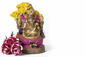 Happy Ganesh Chaturthi - Clay Ganesh idol with flowers on white background. photo