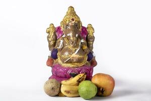 Ganesh Chaturthi is celebrated with clay Ganesh statue and fruits on white background. photo