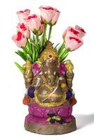 A Ganesh idol made of clay with rose flower on white background. photo