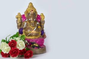 A Ganesh statue made of clay is also a rose flower on white background. photo