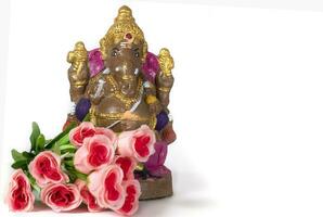 A Ganesh idol made of clay with rose flower on white background. photo