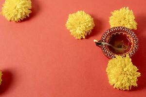 Happy Diwali and Kartika Deepam Festival Greetings - Colorful clay Deepam with yellow flowers on red background photo