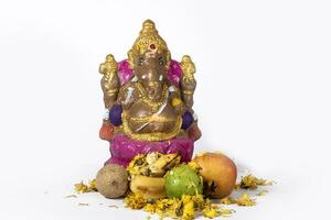 Ganesh Chaturthi is celebrated with a clay idol of Ganesh and flowers and fruits on white background. photo