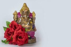 Ganesh idol made of clay with rose flower on white background. photo