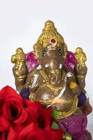 Ganesh idol made of clay with rose flower on white background. photo