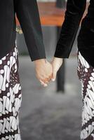 a couple holding hands while standing on a street photo