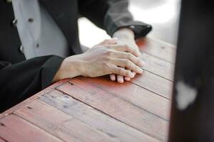 a man's hands resting on a wooden table photo