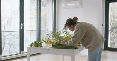 femmina fare nuovo mazzo. ragazza Lavorando nel fiore negozio studio. femmina fioraio artista pulisce fiori per un' bellissimo mazzo, posto di lavoro Visualizza. video