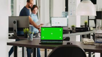 Laptop with greenscreen display on desk in modern startup agency office, wireless computer running isolated mockup copyspace. Empty workstation with chromakey blank device. video