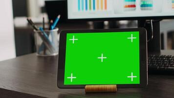 Digital tablet presenting greenscreen display on agency office desk, showing blank chromakey template at empty workstation. Modern mobile device displaying isolated chromakey concept. Close up. video