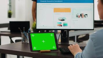 especialista teniendo pantalla verde en tableta y mecanografía mi comercio información en computadora a oficina escritorio, trabajando en creciente pequeño empresa presupuesto. puesta en marcha gerente mira a aislado chromakey disposición. video