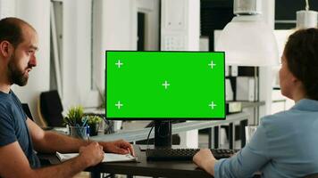 Coworkers using pc with greenscreen on display in creative agency office, planning new partnership. Team of specialists looking at isolated chromakey template, talking about revenue. video