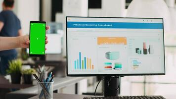 kvinna innehav telefon med grönskärm på företag kontor skrivbord, börja anställd ser på tom copy Displa på smartphone. person arbetssätt med isolerat design mall på telefon. video
